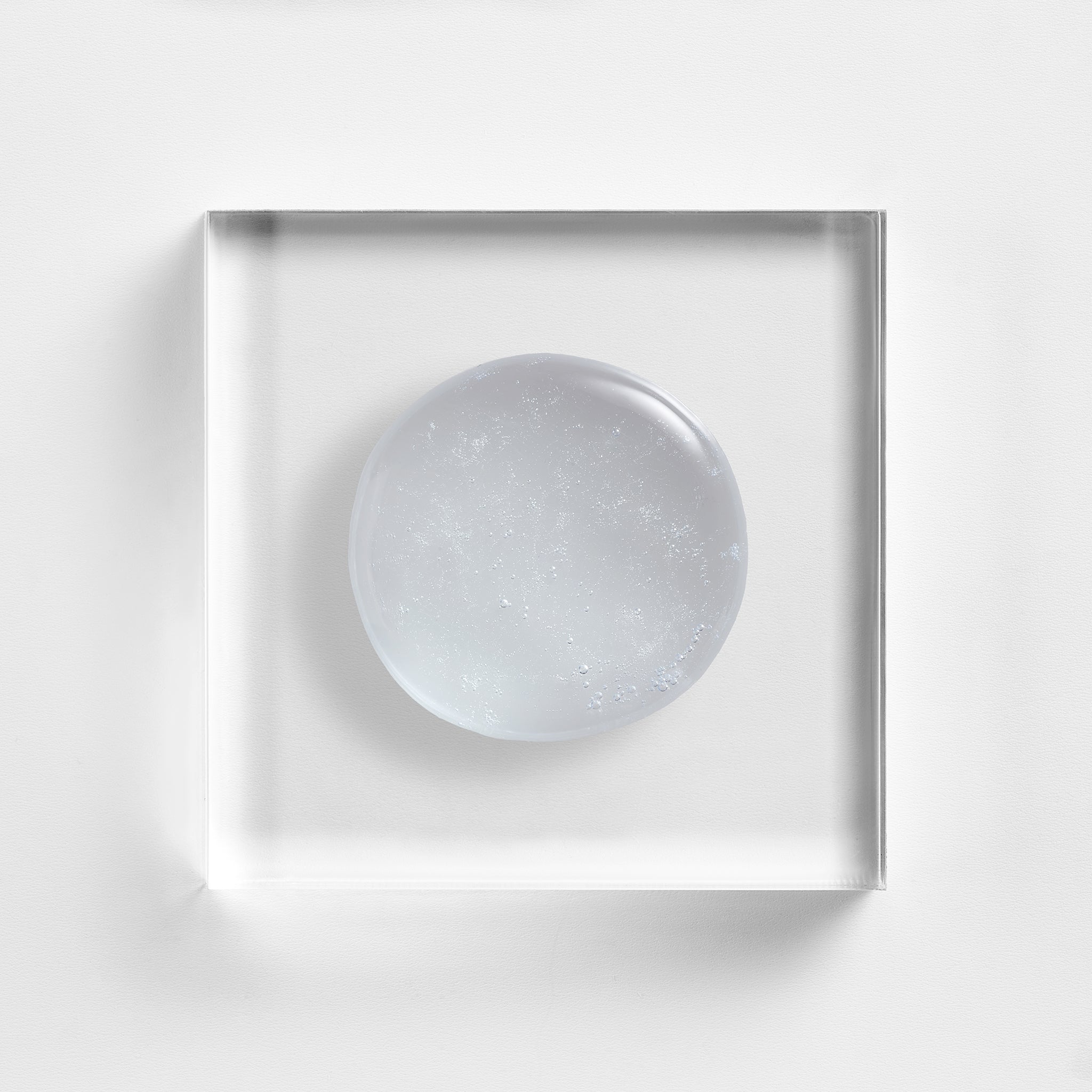 NEOVA Cu3 Gentle Cleanser on a clear acrylic block. The top-down macro view shows the facial cleanser is a transparent, colorless gel with many tiny, suspended oxygen bubbles throughout, giving it a fresh and aerated appearance.