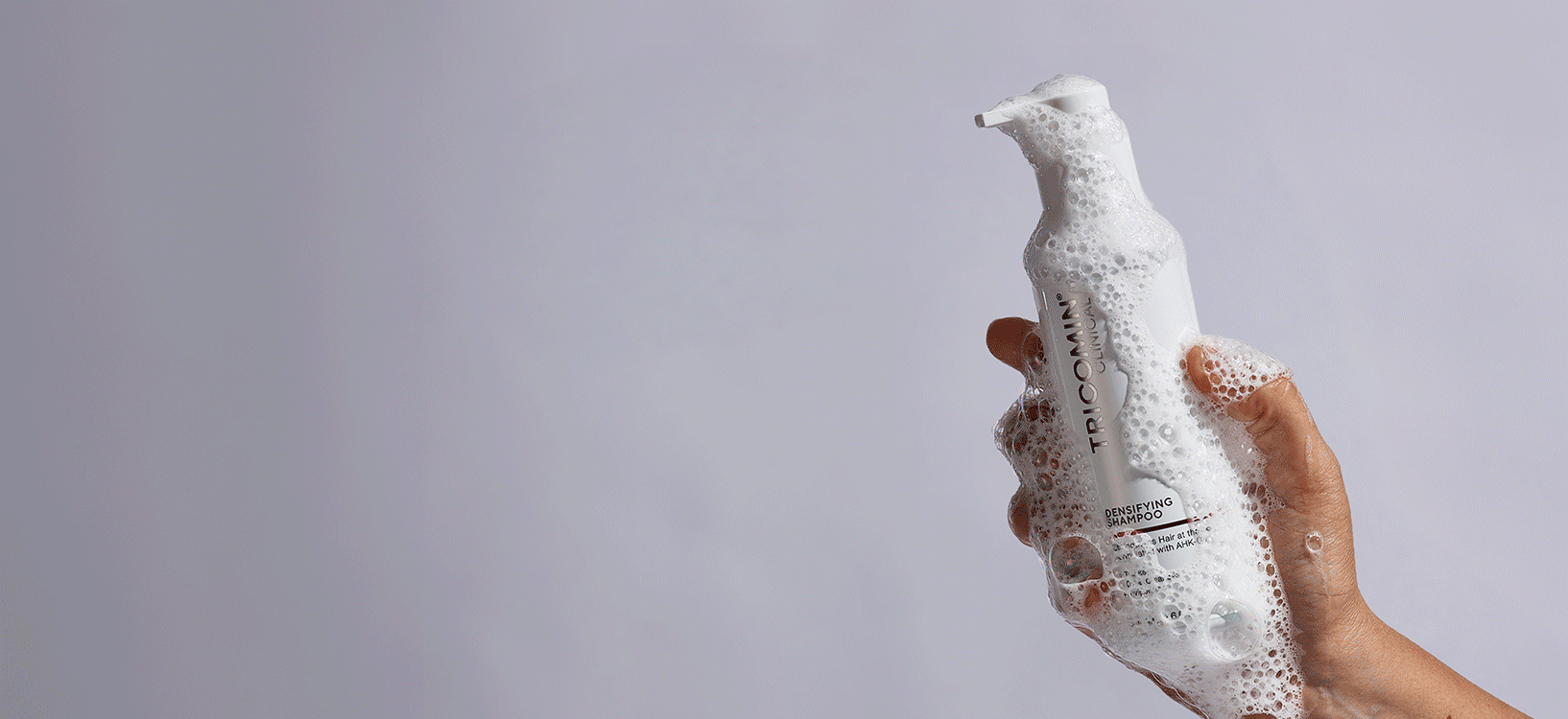 NEOVA - Tricomin Hair Care - A gif of hands holding various bottles of Tricomin Clinical formulas, such as the Densifying Shampoo, Fortifying Conditioner, and 1% AHK-Cu Treatment Spray, each with some product dispensed, against a gray backdrop.