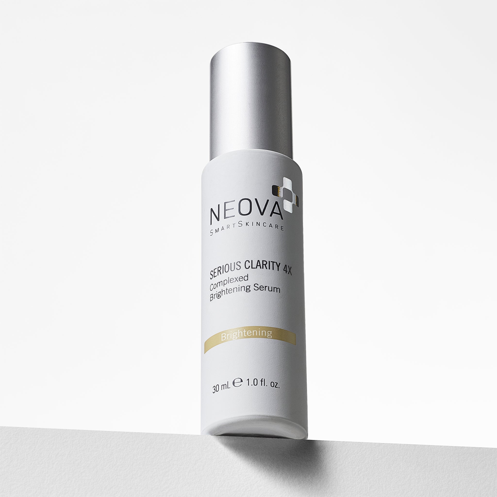 NEOVA Serious Clarity 4X in a white cylindrical bottle of. The front label describes it as a "Complexed Brightening Serum" and features a yellow "Brightening" banner. The bottle has a brushed silver cap and contains 1.0 fl. oz. (30 ml), shown standing on a white surface against a clean, minimalist background.