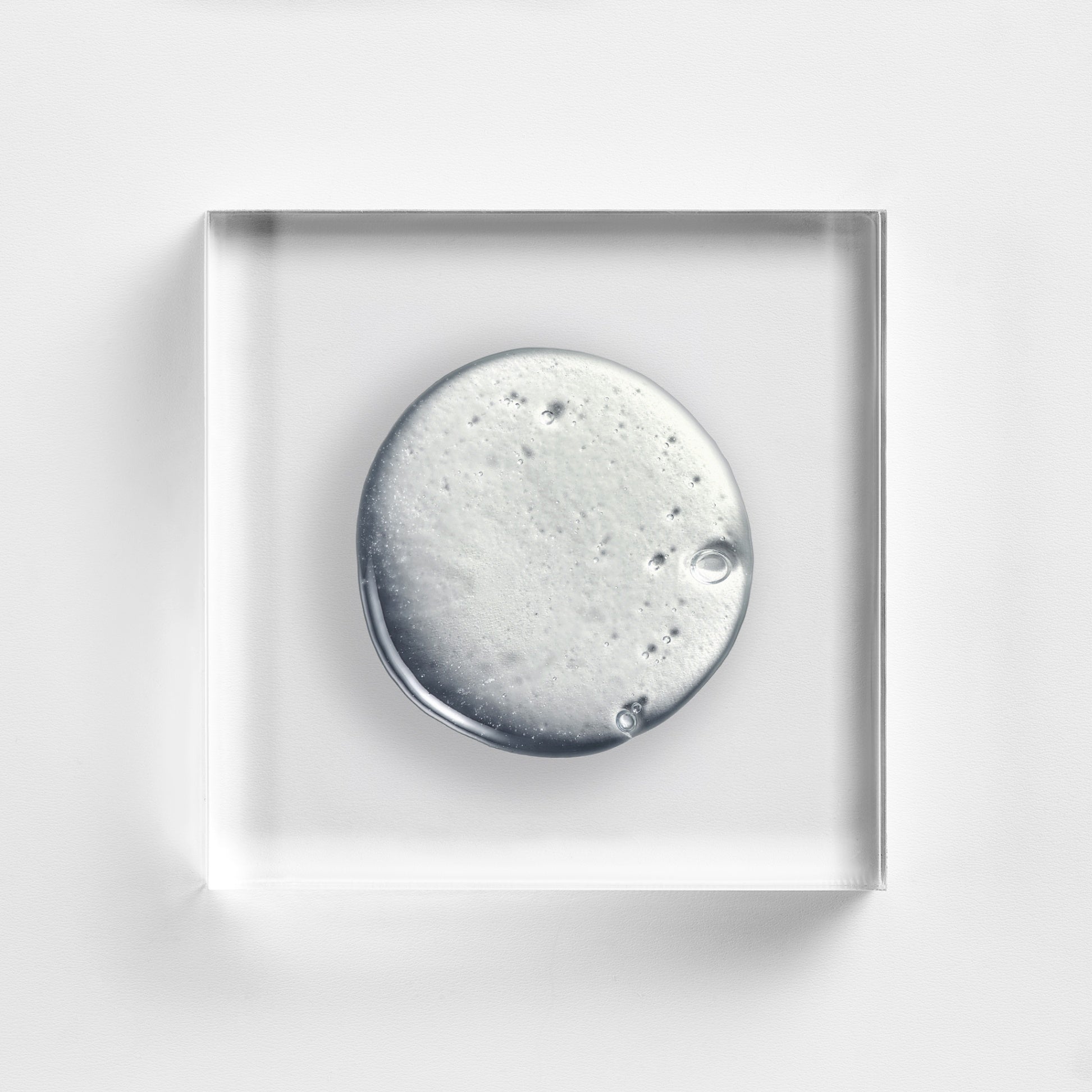 NEOVA Tricomin Densifying Shampoo texture closeup, showcasing the clinical pearlescent liquid formula on a glass tile. This revitalizing shampoo uses copper peptide technology to cleanse the scalp and reinforce hair thinning for a denser, fuller appearance.