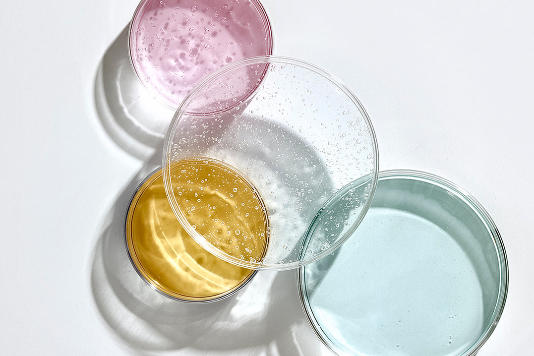 NEOVA Alpha Beta Retinol Science - Four round containers with different colored contents on a light gray background; representing combined AHA, BHA, and retinol exfoliation technology.