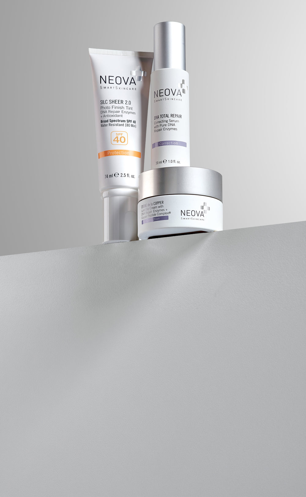 NEOVA - Our Story - Three skincare products from NEOVA, a sunscreen, serum, and moisturizer, on a gray ledge with a grey background
