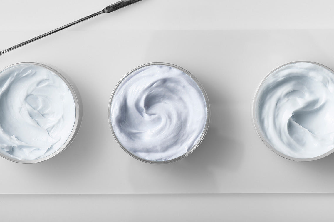 NEOVA Copper Peptide Complex - Three bowls of off-white moisturizing cream containing copper peptides with a metallic mixer on a light gray background