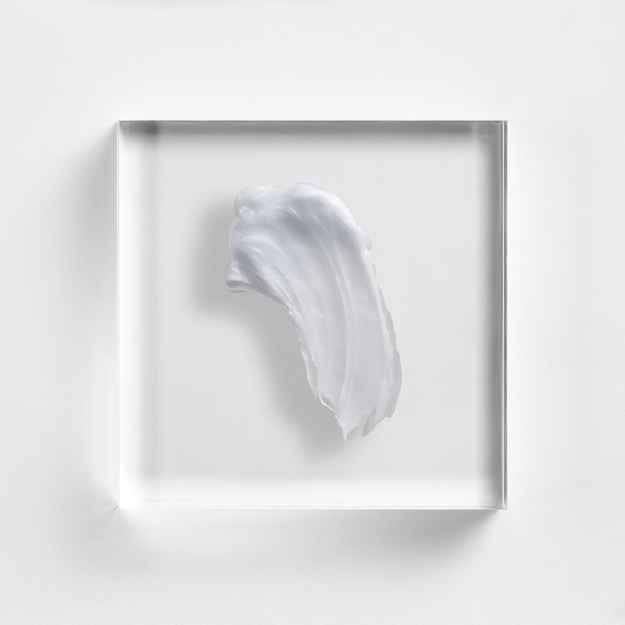 NEOVA Cu3 Lip Repair on a clear acrylic square. The top-down macro view shows the product is a thick, translucent white ointment with visible ridges from being swiped, suggesting a rich, balmy consistency. The composition is minimalist and brightly lit, highlighting the product's protective and emollient quality.