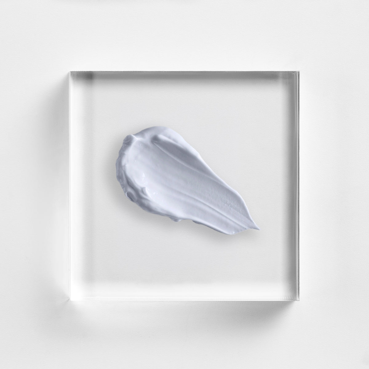 NEOVA Cu3 Recovery Lotion texture on a clear acrylic square. The top-down macro view of the skincare lotion shows an opaque lavender-grey color and a creamy texture. It is centered against a textured white background with soft, clean lighting.