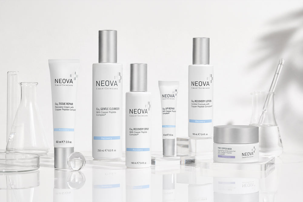 NEOVA - Cu3 Recovery Solution - Six NEOVA Recovery skincare products lined up on a white background with lab glassware. From left to right: Cu3 Tissue Repair, Cu3 Gentle Cleanser, Cu3 Recovery Spray, Cu3 Lip Repair, Cu3 Recovery Lotion, Pure Copper Mask