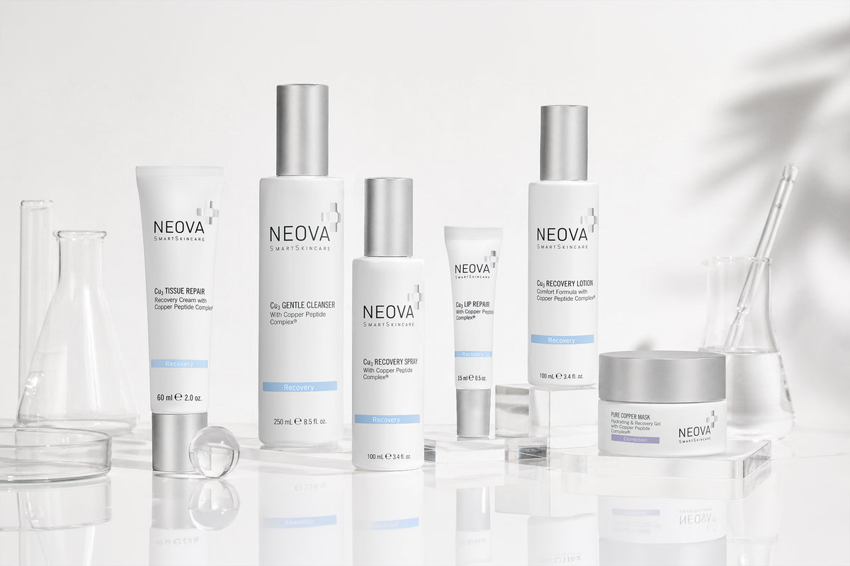 NEOVA - Cu3 Recovery Solution - Six NEOVA Recovery skincare products lined up on a white background with lab glassware. From left to right: Cu3 Tissue Repair, Cu3 Gentle Cleanser, Cu3 Recovery Spray, Cu3 Lip Repair, Cu3 Recovery Lotion, Pure Copper Mask