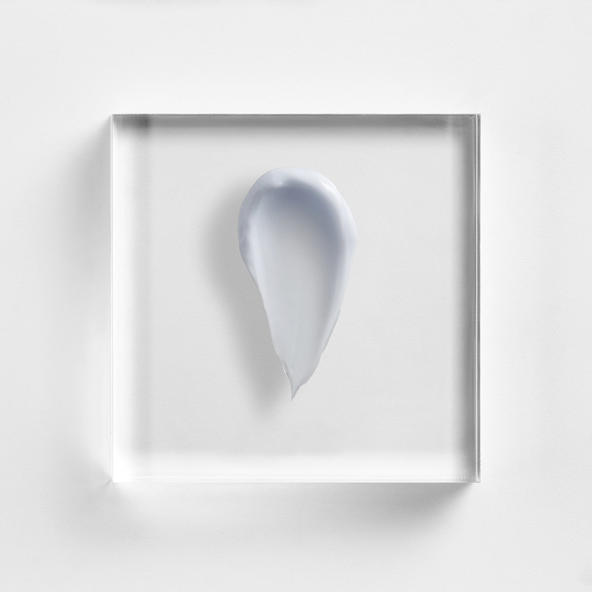 NEOVA Cu3 Tissue Repair cream on a clear acrylic square. The top-down macro view shows the cream has a distinct, pale lavender-blue tint and a thick, smooth, opaque consistency. The composition is brightly lit against a textured white background, highlighting the product's rich and soothing texture.