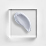 NEOVA Daily Moisture cream on a clear acrylic block. The top-down, macro composition shows the cream is a clean, opaque white with a rich, velvety appearance and a slight glossy sheen. It is centered against a minimalist, white background, highlighting its thick and hydrating consistency.