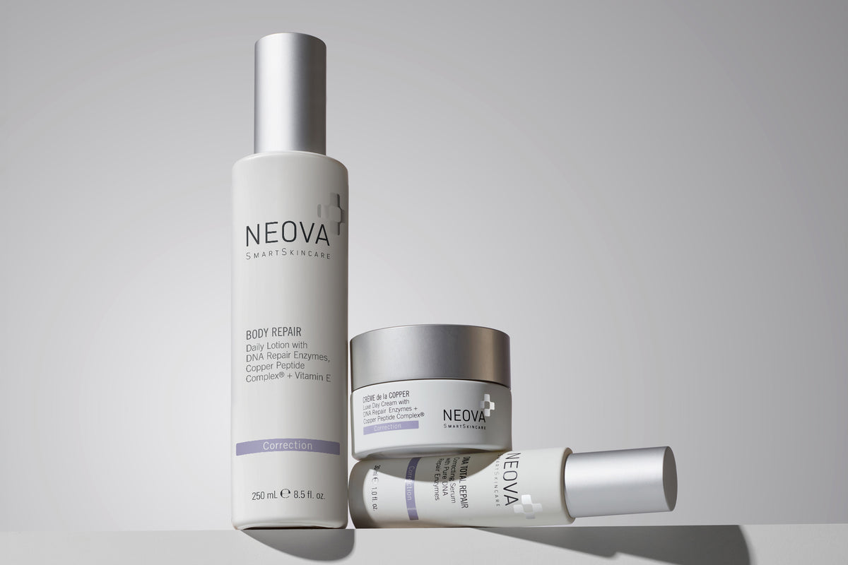 NEOVA DNA Repair skincare products on a gray background. From left to right: Body Repair daily lotion, Creme da la Copper luxe day cream, DNA Total Repair correcting serum
