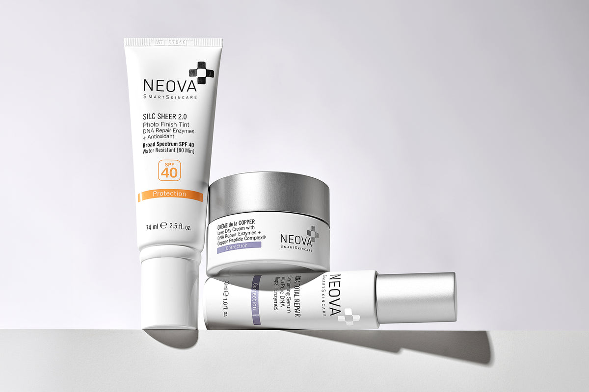 NEOVA DNA Repair Enzyme Science skincare on a grey background. From left to right: Silc Sheer 2.0 SPF 40, Creme de la Copper luxe day cream and DNA Total Repair correcting serum.