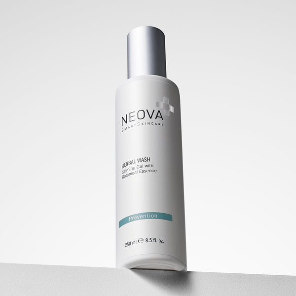 NEOVA Herbal Wash, a gentle gel cleanser with botanical extracts, in a tall, white cylindrical bottle. The front label categorizes it under a blue "Prevention" banner. The bottle features a brushed silver cap and contains 8.5 fl. oz. (250 ml). It is shown standing on a white ledge against a clean, minimalist background with soft lighting.