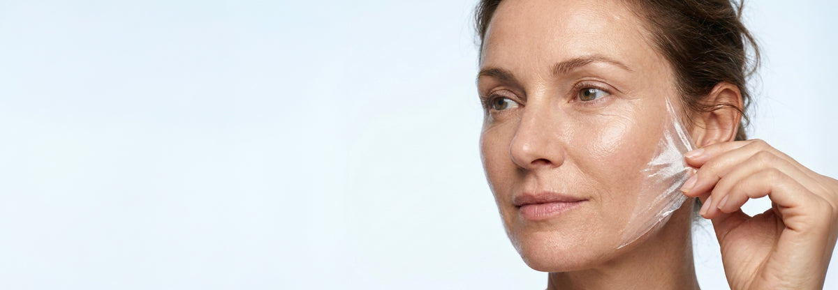 NEOVA - Serious Glypeel - A close-up of a woman peeling a transparent peel-off skin mask from her cheek, set against a clean, light blue background.
