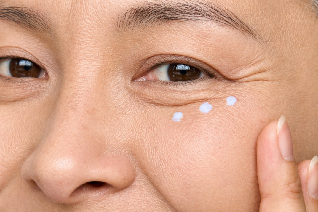 NEOVA Illuminating Eye Serum – application: Close-up of under-eye area showing eye serum being gently applied to reduce dark circles, puffiness, and fine lines.