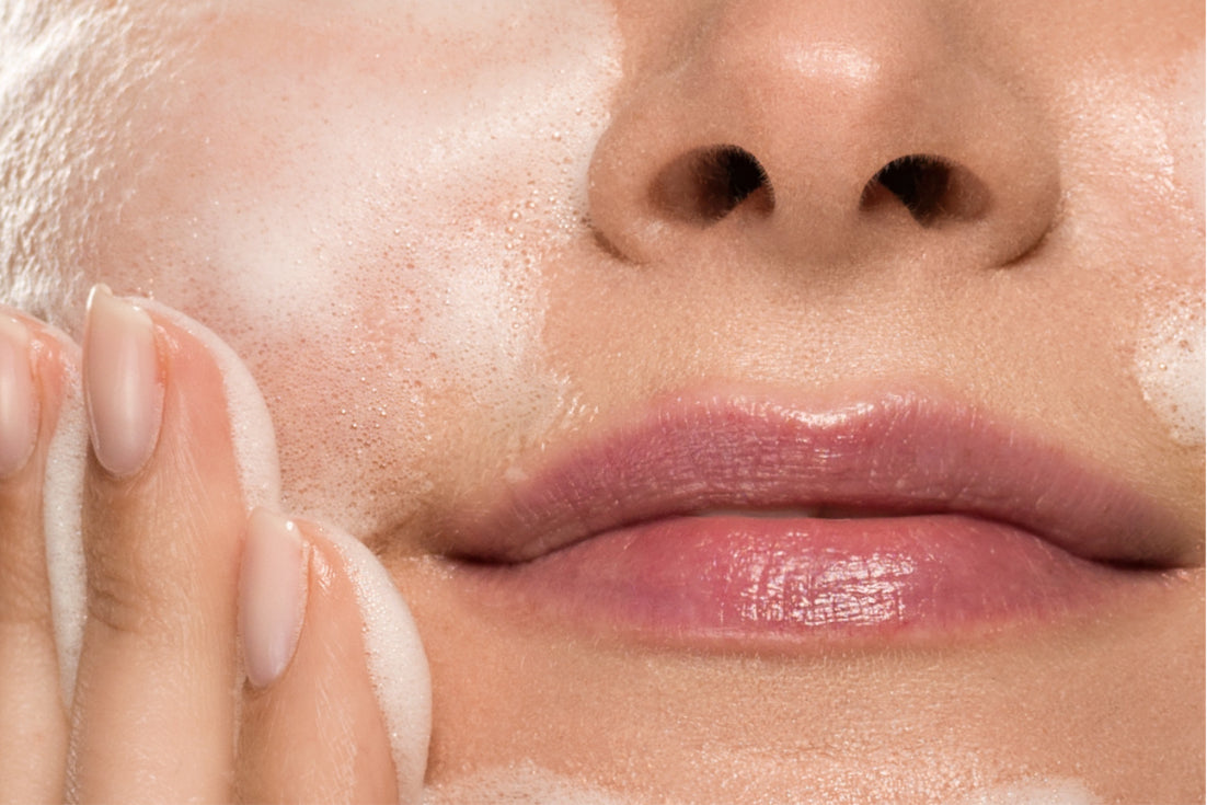 NEOVA Microfoliant Cleanser – application: Close-up of lower face showing exfoliating cleanser being massaged into skin to remove dead skin cells, unclog pores, and improve texture.