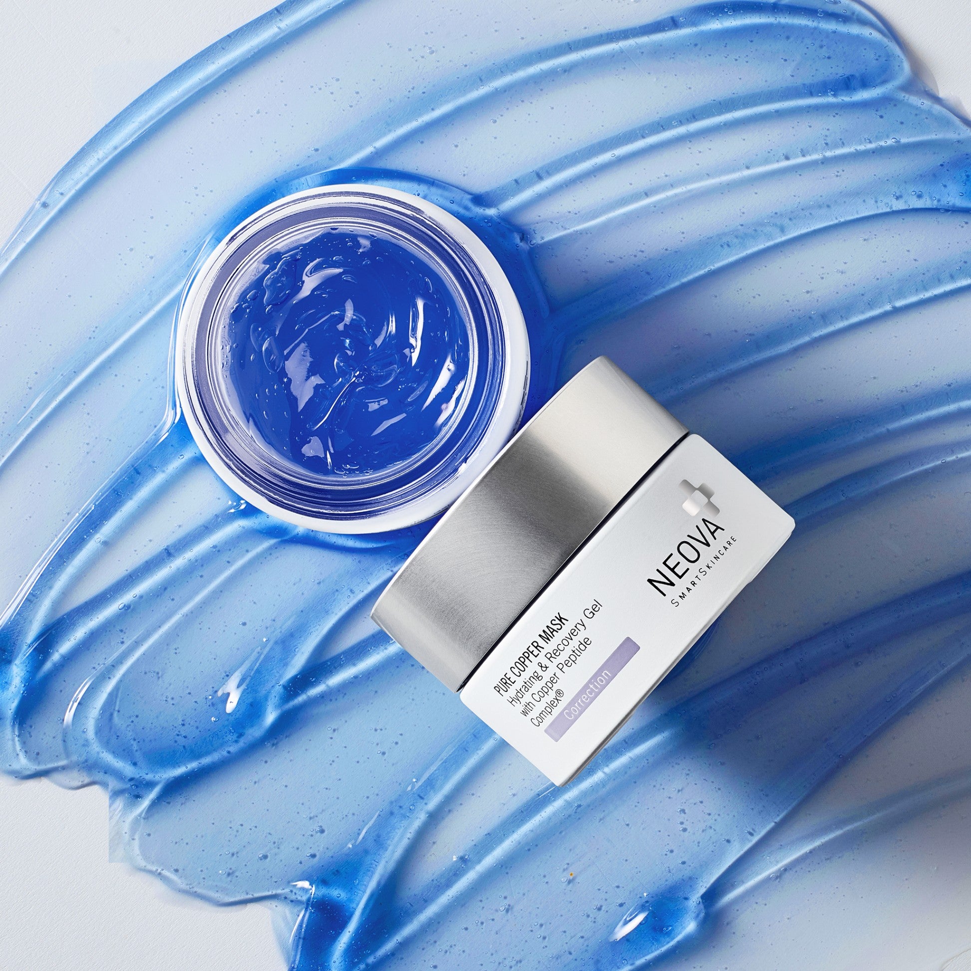NEOVA - Pure Copper Mask - NEOVA Pure Copper Mask product jar displayed beside an open container of vibrant blue gel on layered blue skincare texture smears, highlighting the hydrating and recovery-focused copper peptide formula.