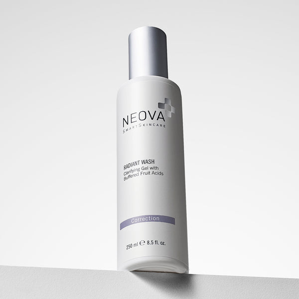 NEOVA Radiant Wash in a tall, white cylindrical bottle. The front label identifies it as a "Clarifying Gel with Buffered Fruit Acids", categorizing it under a purple "Correction" banner. The bottle features a brushed silver cap and contains 8.5 fl. oz. (250 ml), shown standing on a white ledge against a clean, bright minimalist background.
