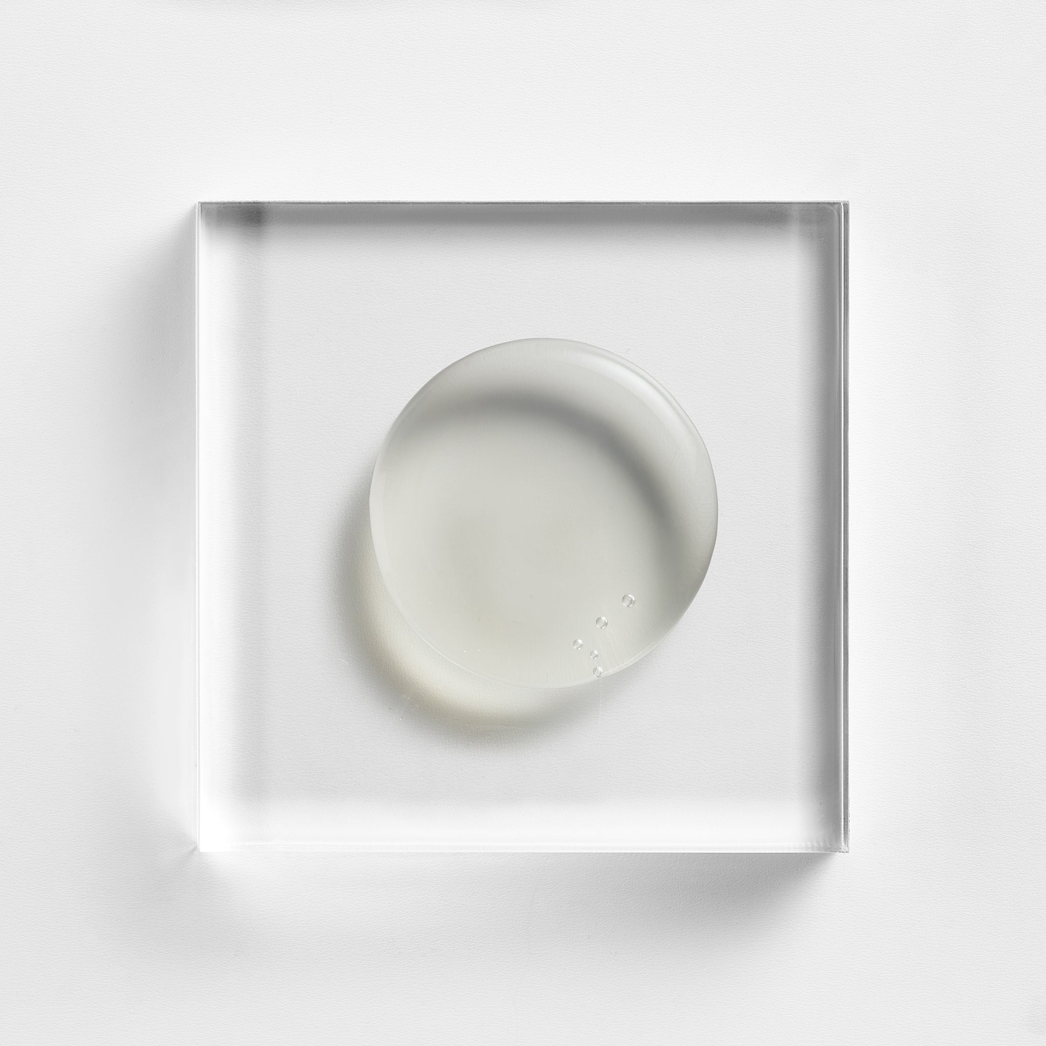NEOVA Serious Glypeel on a clear acrylic block. The top-down, square macro view shows the product is a transparent, colorless gel with a smooth, high-gloss finish and a firm, jelly-like consistency. It is centered and brightly lit against a textured white background, emphasizing its clear and cooling appearance.