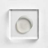 NEOVA Serious Glypeel on a clear acrylic block. The top-down, square macro view shows the product is a transparent, colorless gel with a smooth, high-gloss finish and a firm, jelly-like consistency. It is centered and brightly lit against a textured white background, emphasizing its clear and cooling appearance.