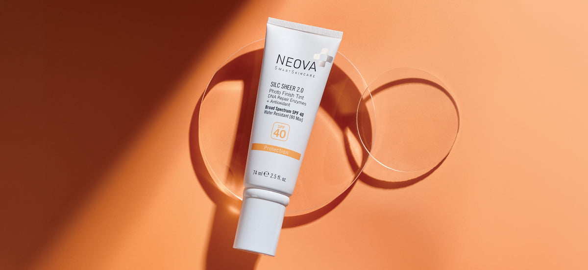 NEOVA Silc Sheer 2.0 Broad Spectrum SPF 40 on a horizontal orange background and two abstract glass disks with subtle shadow effects