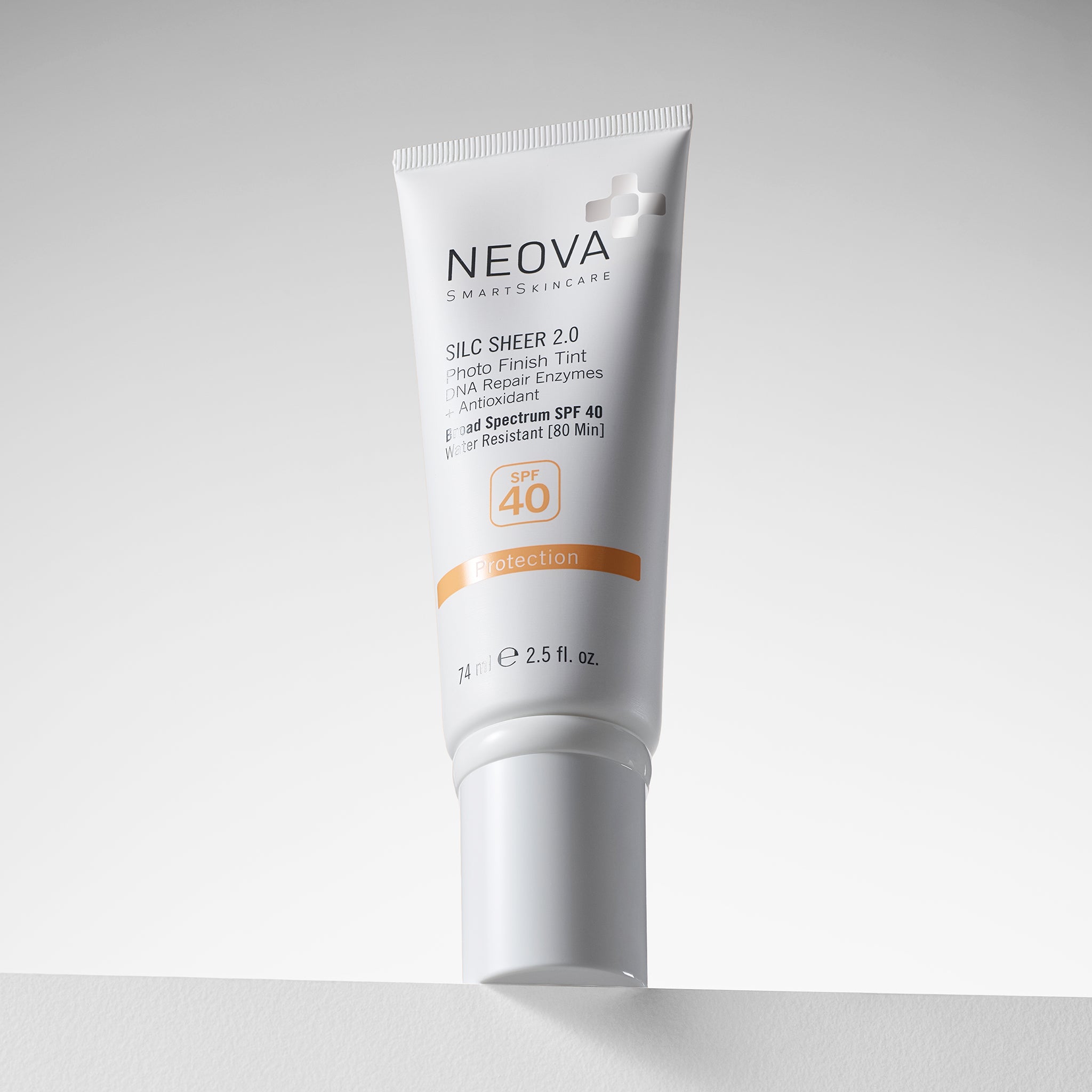 NEOVA Silc Sheer 2.0 Broad Spectrum SPF 40 sunscreen in a white squeeze tube. The packaging features clean black and orange text highlighting a "Photo Finish Tint", "DNA Repair Enzymes + Antioxidant". It notes the formula is water-resistant for 80 minutes and contains 2.5 fl. oz. (74 ml). The tinted sunscreen is angled slightly, resting on a white surface against a minimalist, bright white background.