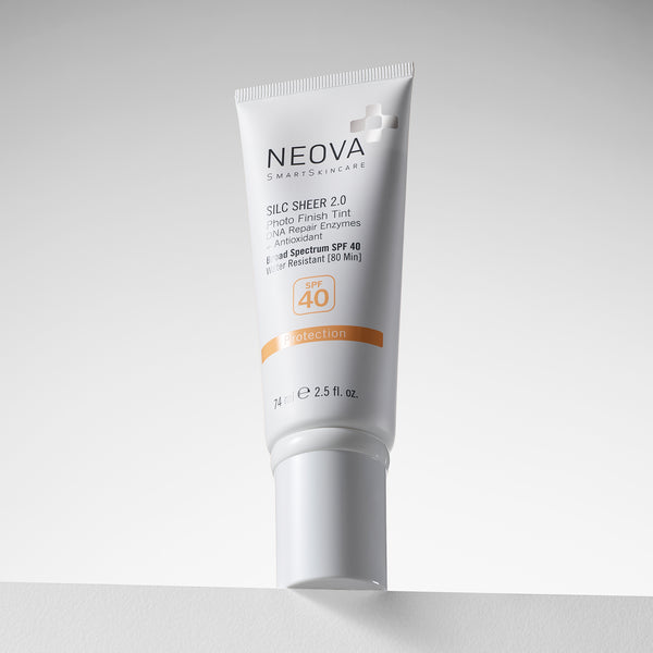 NEOVA Silc Sheer 2.0 Broad Spectrum SPF 40 sunscreen in a white squeeze tube. The packaging features clean black and orange text highlighting a "Photo Finish Tint", "DNA Repair Enzymes + Antioxidant". It notes the formula is water-resistant for 80 minutes and contains 2.5 fl. oz. (74 ml). The tinted sunscreen is angled slightly, resting on a white surface against a minimalist, bright white background.