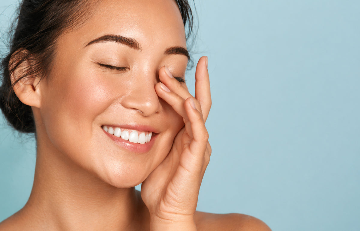 NEOVA | Woman touching her radiant, glowing face after following a spring glow routine with a blue background