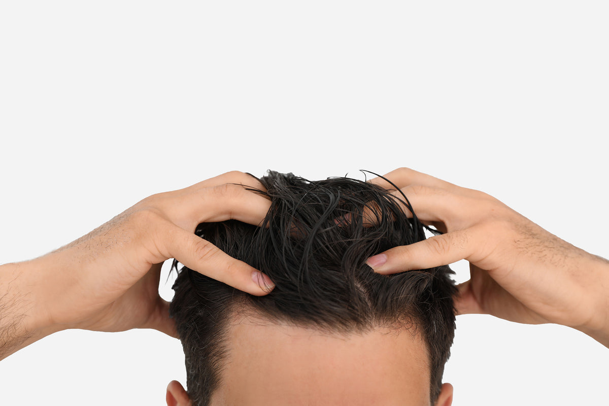 NEOVA Tricomin 1% AHK-Cu Treatment Spray - application image: Person touching their wet hair with both hands on a white background.