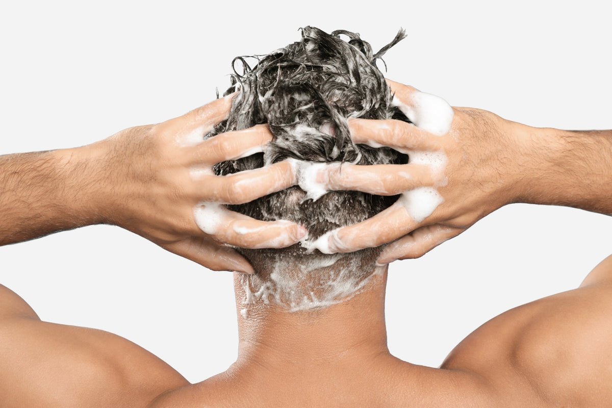 NEOVA Tricomin Densifying Shampoo   - application image: Person washing their hair with shampoo against a white background. The image shows the white suds, referring to the shampoo's cleaning capabilities.
