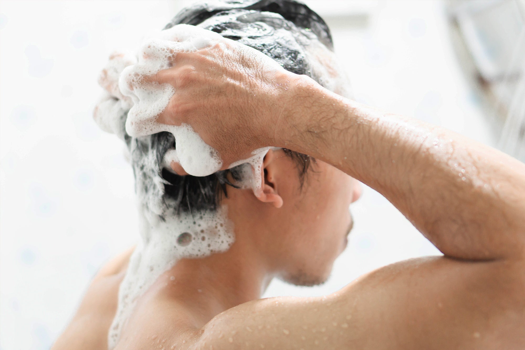 NEOVA - Hair Care - Mega Menu -Person washing their hair with a sudsy shampoo in a bathroom setting