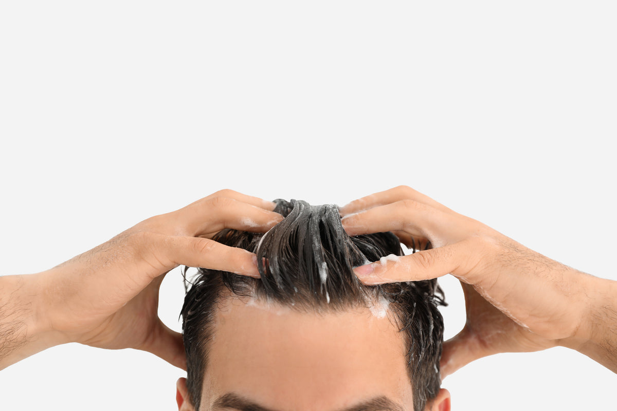 NEOVA Tricomin Hair Strengthening System - application image: Person applying hair strengthening shampoo to their hair against a white background