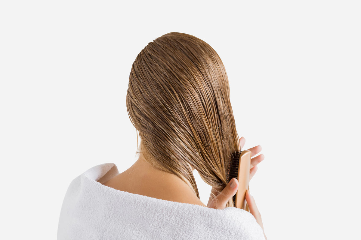 NEOVA Tricomin Travel System Kit - application image: Person with long, straight hair using a comb through their wet, treated hair on a white background